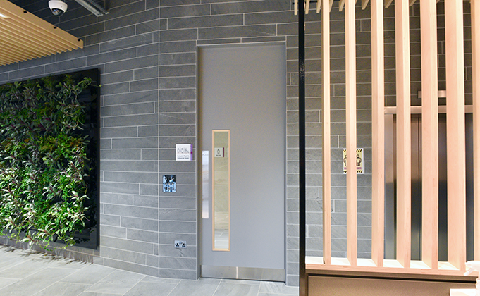 Extra height grey timber door in modern office on industrial looking stone wall