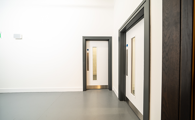 White timber fire doors_paint grade finish doors_vision panel_grey frame_services area of commercial building_facilities area_sports education building